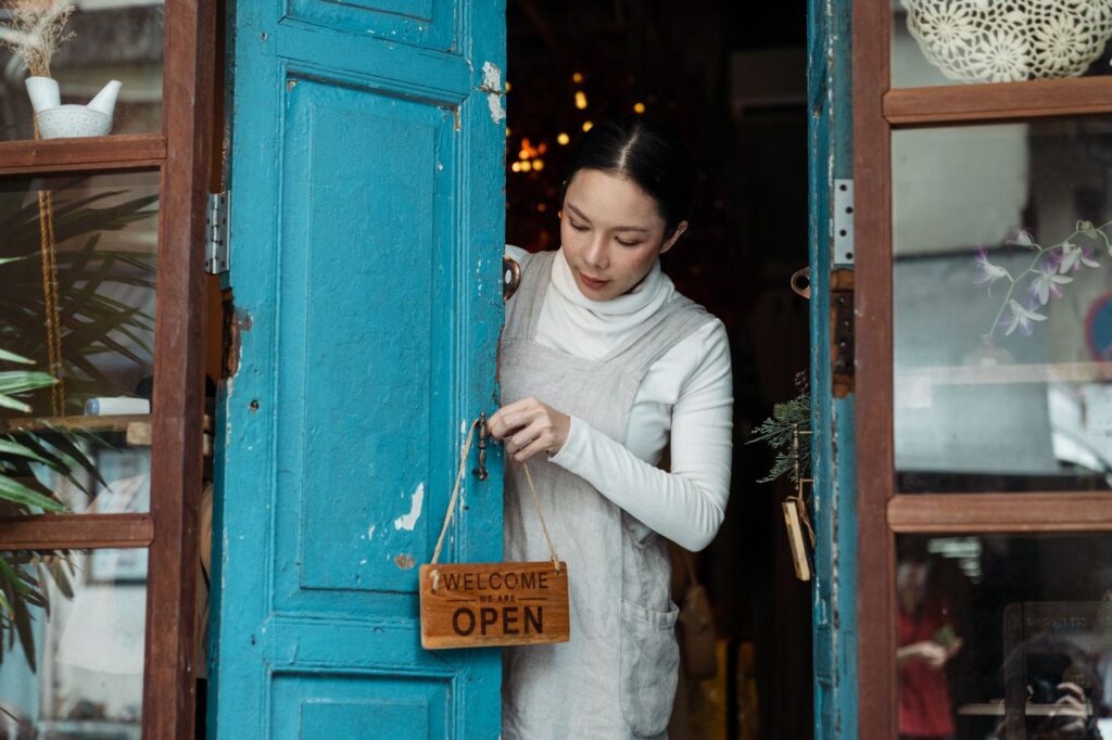 Small business owner hanging an open sign on the door of her shop, where a BIR Certificate of Registration must also be displayed conspicuously