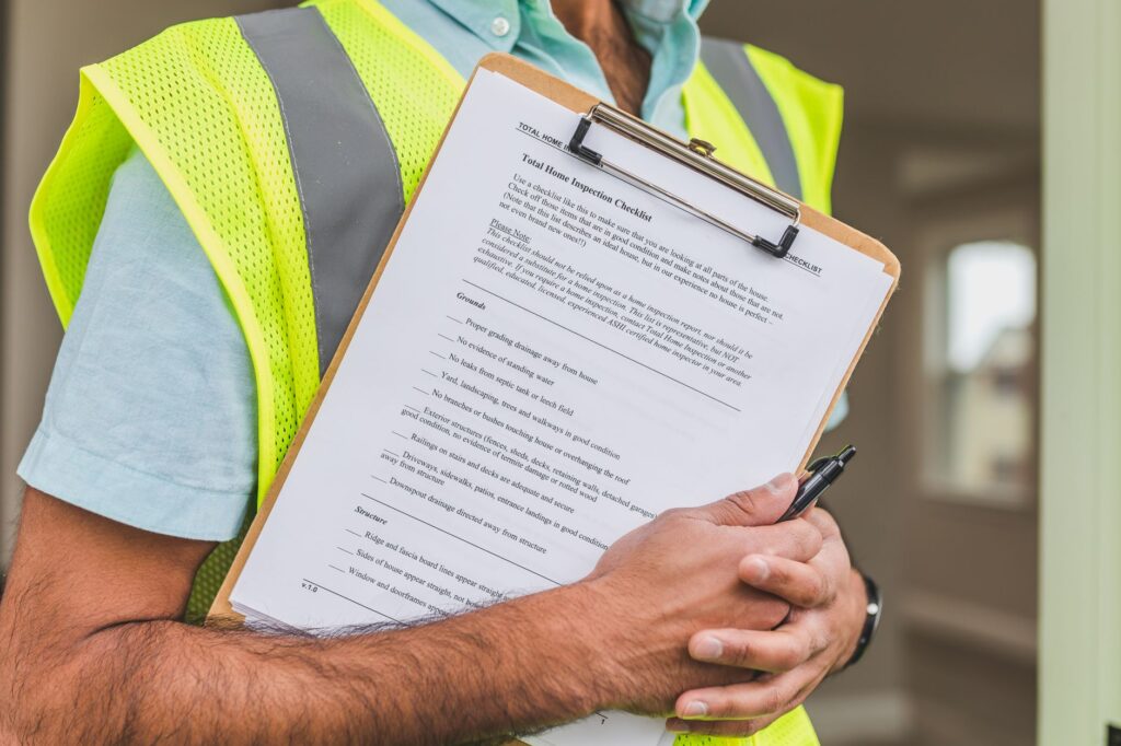 Inspector in a hi-vis safety vest holding a compliance checklist on a clipboard, illustrating OSH inspection requirements under DOLE Department Order 198-18