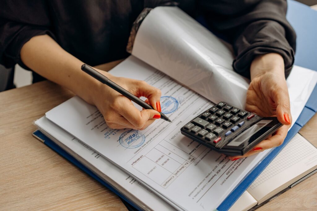 Accountant reviewing stamped compliance documents and using a calculator, representing DOLE labor standards documentation requirements for small businesses