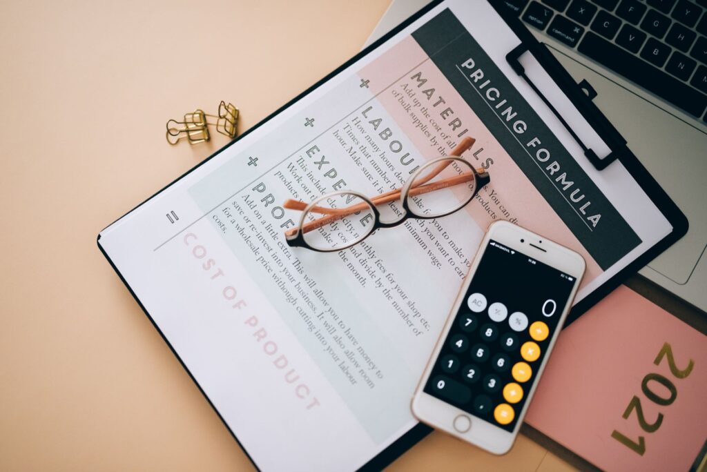 Pricing formula document with calculator and glasses for payroll cost analysis
