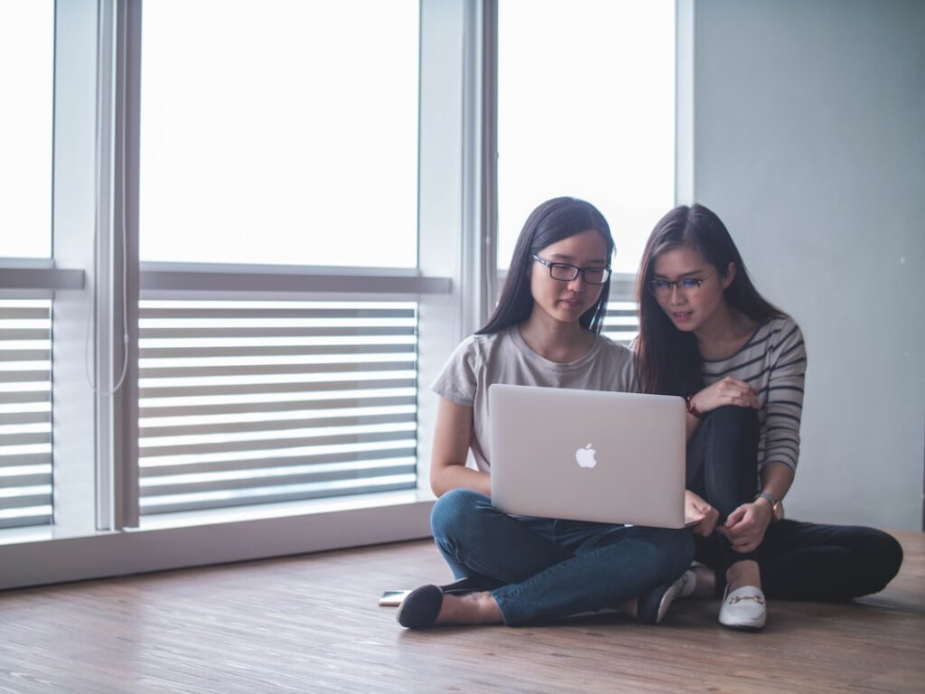 Two young women reviewing business registration requirements on a laptop in Davao