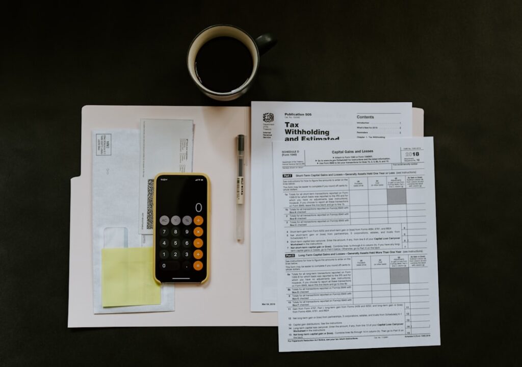 Tax withholding form, calculator, and coffee on a desk representing legal fee structures and billing transparency in Davao law firms