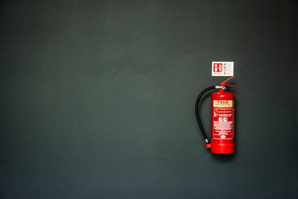 Red fire extinguisher mounted on a gray wall with a fire safety sign, representing the Fire Safety Inspection Certificate requirement for the Mayor's Permit in Davao City