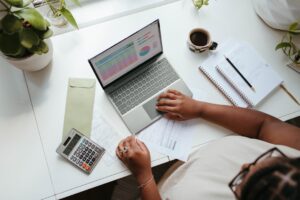 Business owner working on laptop with financial documents, calculator and coffee — illustrating BIR Philippines online tax filing for SMEs
