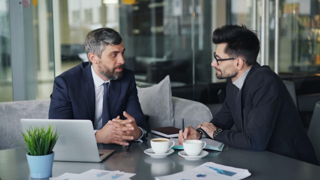Two business professionals in suits discussing documents during a legal consultation meeting