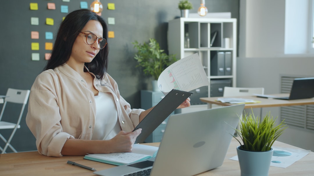 HR manager reviewing payroll compliance documents at office desk with laptop