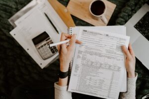 Person reviewing a tax registration form with a calculator, coffee cup, and laptop on the desk — illustrating BIR Form 1901 filing for freelancers in the Philippines