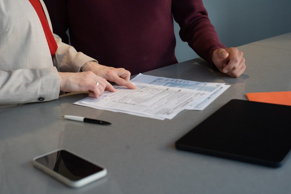 Two people reviewing official paperwork and application forms at a desk, illustrating the document submission process at the Davao City BPLO